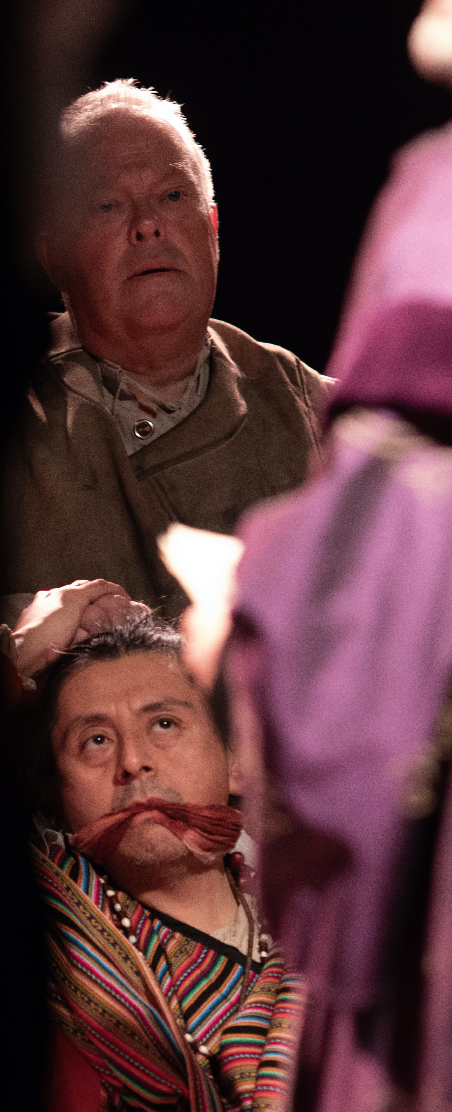 White man holding the head of Indigenous man who is gagged