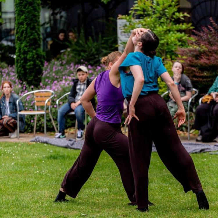 Two dancers on green grass with audience in background
